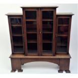 An Arts Crafts oak breakfront bookcase, with four glazed doors enclosing adjustable shelves, the