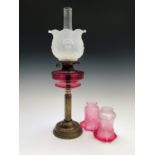 A Victorian brass oil lamp with cranberry glass reservoir ,overall height 67.5cm, together with