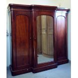 A Victorian mahogany triple wardrobe, with a central mirrored door flanked by two arched panelled