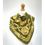 A silk scarf by Chanel, in olive green with gold chain link design, central Chanel logo. 87cm x