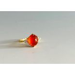 An 18ct gold fire opal ring each shoulder with a diamond trefoil.Condition report: The opal 11.6 x