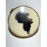 An 18th century gold mounted memorial locket, with a silhouette portrait of a lady, plaited hair