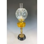 A brass oil lamp, with amber glass reservoir and etched glass globe. Height 63cm.
