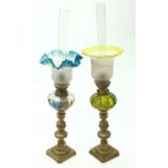 Two glass and brass oil lamps, surmounted on a pair of Victorian brass candlesticks. Height 40cm.