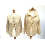 Two Aran style hand knitted cream wool cardigans, one with leather buttons, the other with metal