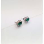 A pair of 18ct white gold oval emerald and diamond cluster earringsCondition report: No obvious