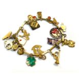 A 14ct gold bracelet hung with charms of various purities, some enamelled, but also a Victorian