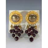 A pair of Eric Beamon earrings, gold colour discs with suspended red beads, boxed in original Eric