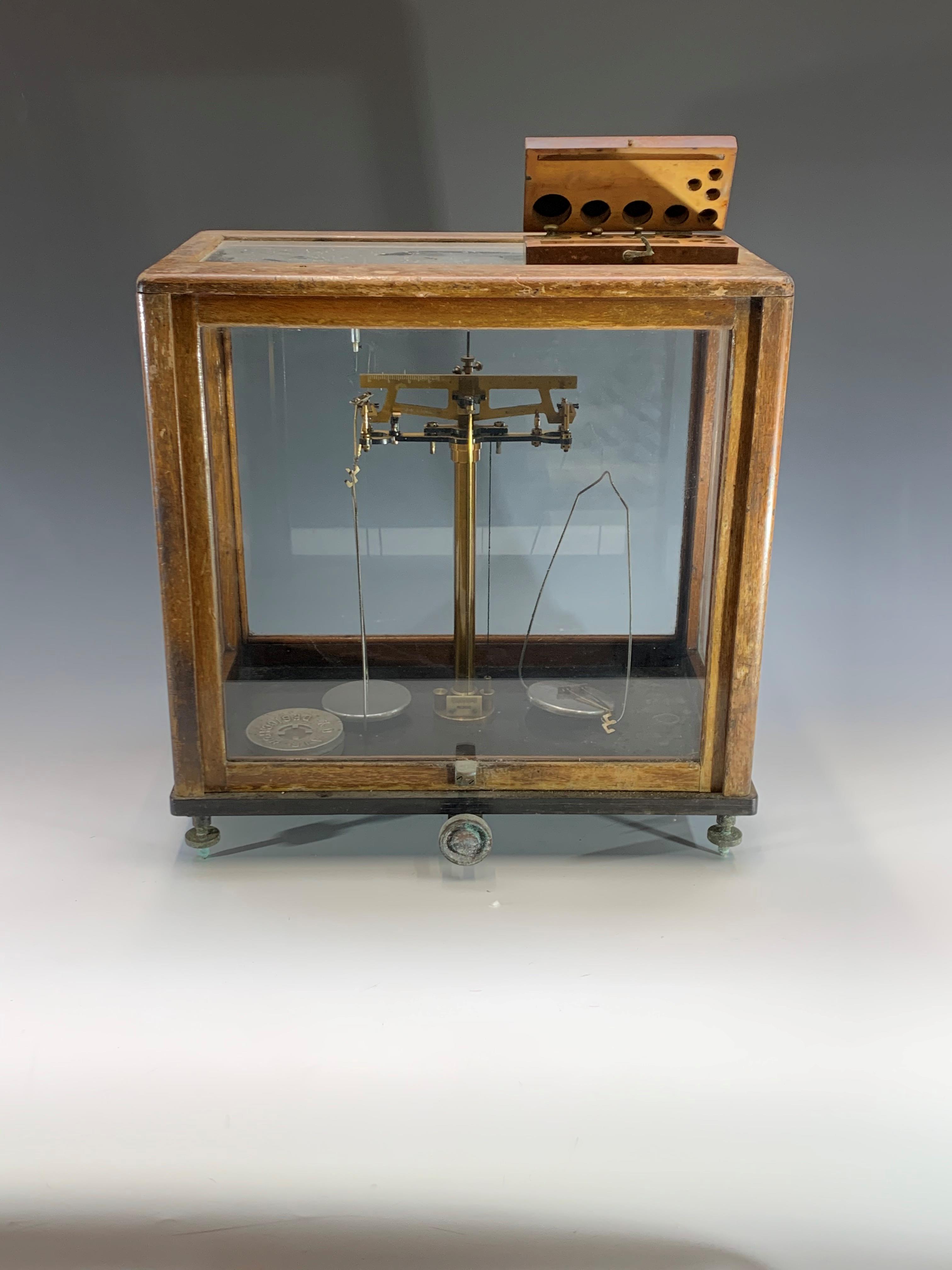 A set of laboratory scales, contained in a glazed case, height 43cm, with part set of cased