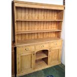 A pine dresser, the rack with two shelves, the lower part with three drawers above two panelled