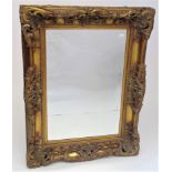 An ornate gilt framed rectangular wall mirror, modern, fitted a bevel edge plate, 124 X 93cm.