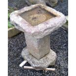 A granite bird bath of roughly hewn form, on a square pillar. Height 68cm.Condition report: The