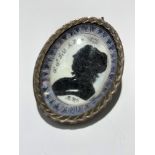 An 18th century mourning silhouette in silver pendant mount, signed with initials RW and