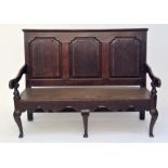 A George III oak and mahogany crossbanded settle, with a triple panelled back and cabriole legs,