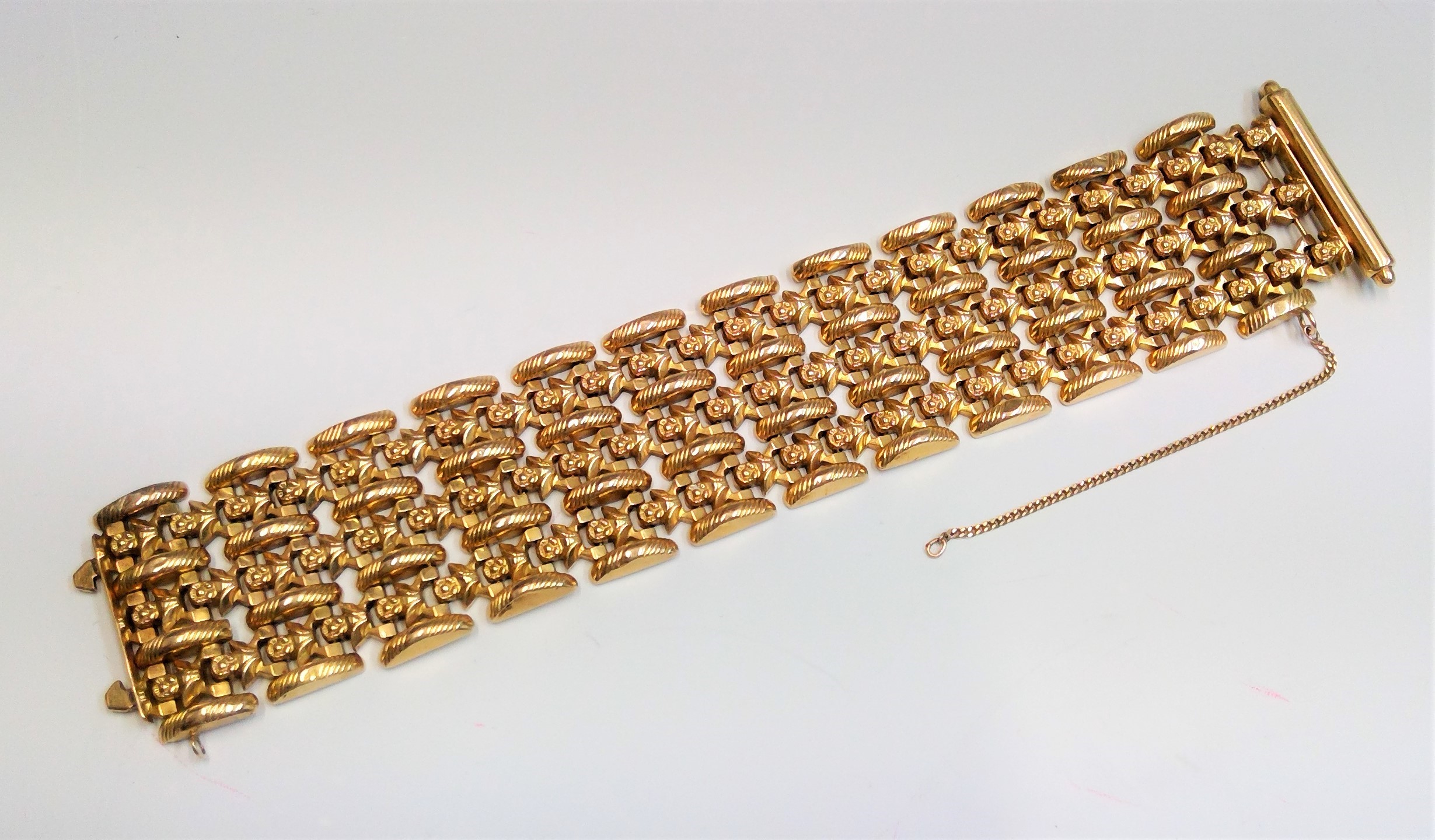 A 1950's 18ct gold braceletwith stands of flowers and ribbed links and patent sprung squeeze clasp