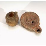 A terracotta oil lamp, probably Roman, moulded with a figure and a dog, length 10cm, and a small