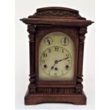 An early 20th century oak cased German mantel clock with silvered engraved dial and striking with
