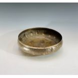 An Indian white metal shallow bowl, the body with plain shaped cartouches and scrolling leafy