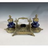 An early 20th century gilt metal desk stand with two ceramic inkwells. Height 14cm, width 34cm.