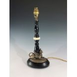 An early 20th century ebonised wood and ivory table lamp, the plated base in the form of a recumbent