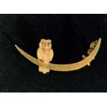 A 9ct two colour gold owl brooch the bird with demantoid garnet eyes perches on a crescent new moon.