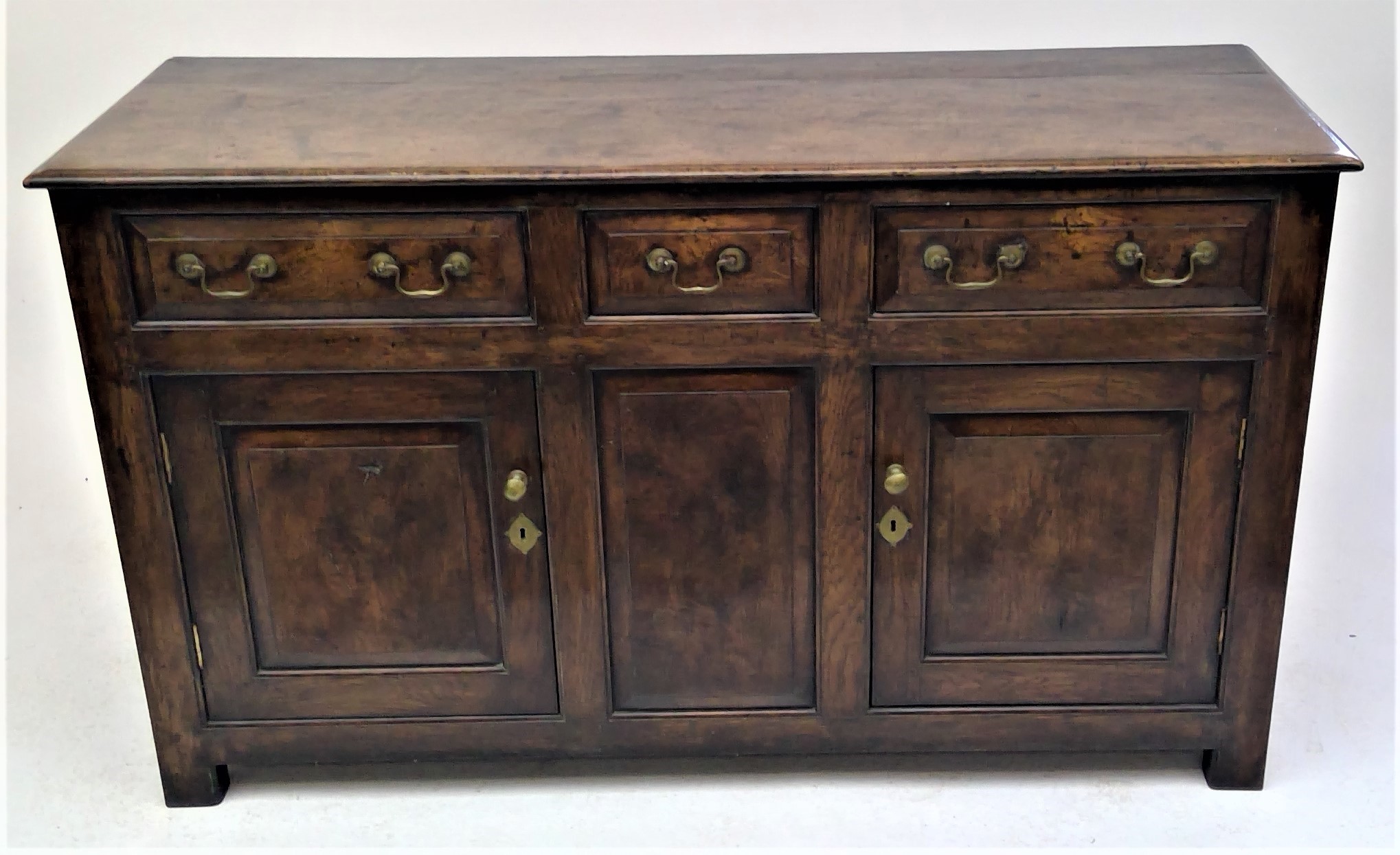 An oak dresser. early 18th century style, with three fielded panel drawers above two doors and a