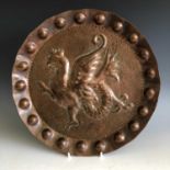 A Cornish art copper charger of circular form, embossed with a wyvern, attributed to George Ernest