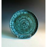 A Troika pottery plate with insciced floral and leaf decoration, embossed 'Troika St Ives' trident