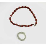 A Chinese jade bracelet, diameter 7cm and a necklace with carved cinnabar lacquer and plain wooden