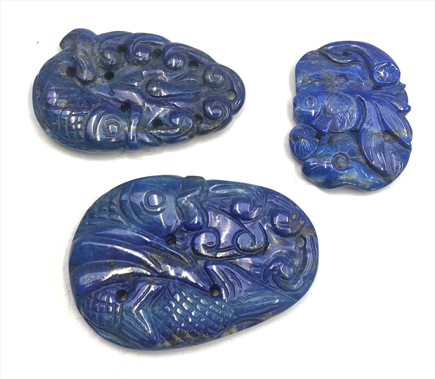 Three Chinese lapis lazuli pendants, each decorated with fish, lengths 6.3cm, 5.5cm and 4.2cm.