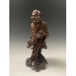 A Chinese carved hardwood figure of buddha, circa 1900, holding a basket, signed paper label, height