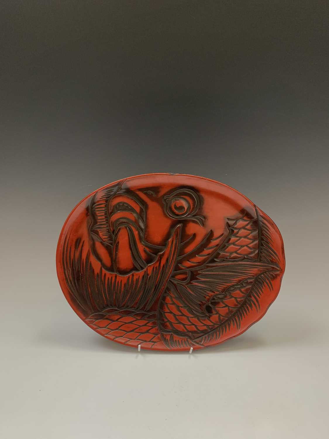 A Japanese red lacquer tray, early 20th century, depicting a koi carp, paper label to verso, 28 x