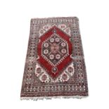A South West Persian rug, the madder field with a charcoal hooked lozenge medallion, with