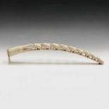 A carved ivory tusk, early 20th century, with a crocodile and procession of nine graduated