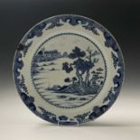 A large Chinese blue and white porcelain charger, 18th century, depicting a riverside scene,