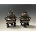 A pair of Japanese bronze censers, each with pierced dragon decorated covers surmounted by a dog