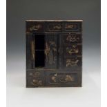 A Japanese black lacquered table cabinet, 19th century, with a pair of sliding doors, seven