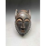 An African carved wood and painted tribal mask, with extended ears. Height 38cm.