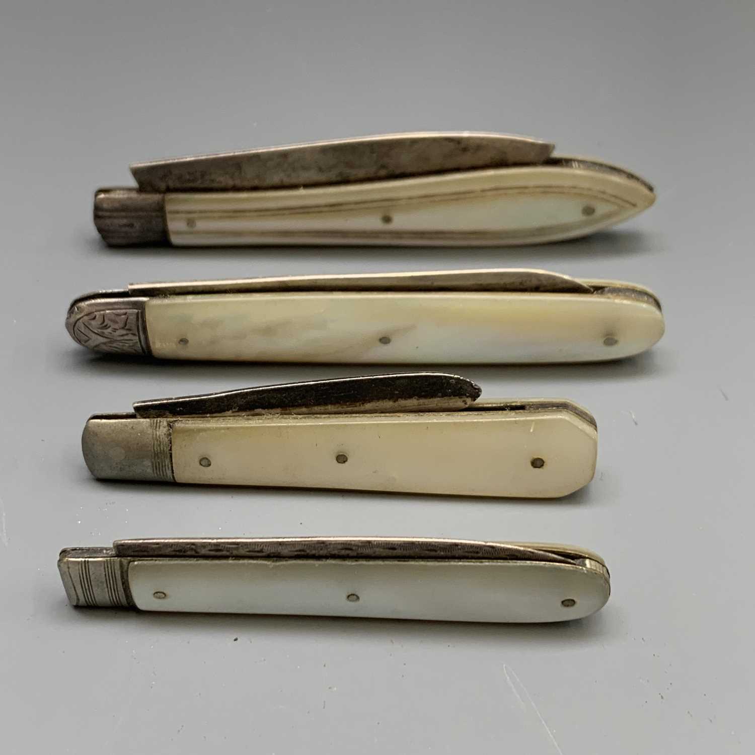 Four fruit knives, each with mother-of-pearl covers and plain folding silver blade