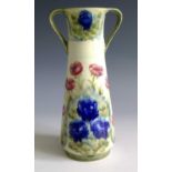 A William Moorcroft twin handled vase, decorated with red and blue poppies, signed to base. Height