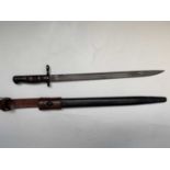 A US Remington 1913 pattern bayonet, with two piece wooden grip, leather scabbard and 1940 leather