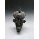A tribal carved softwood mask of slender form. Height 35cm.