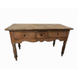 A Victorian pine side table, fitted with three drawers above a shaped frieze and raised on turned