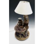 A plaster figural table lamp, modelled as a fisherman making a model boat, on ropework moulded base,