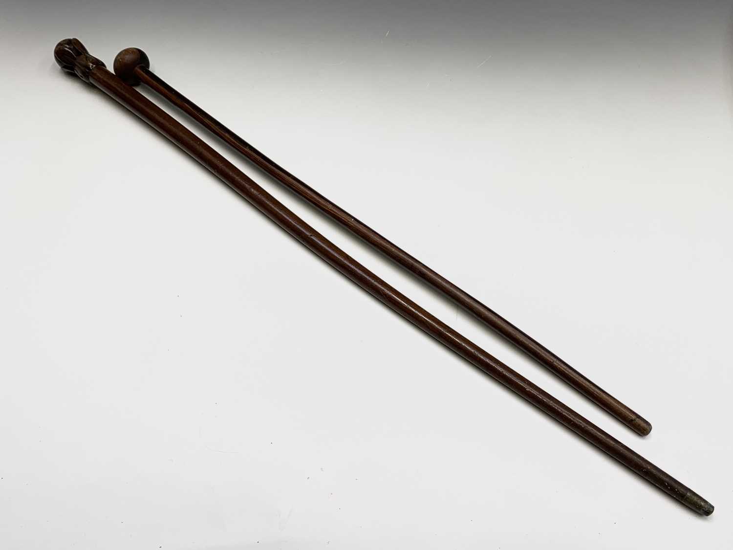 A lignum vitae cane, with turned knop, together with a further cane with carved finial, length