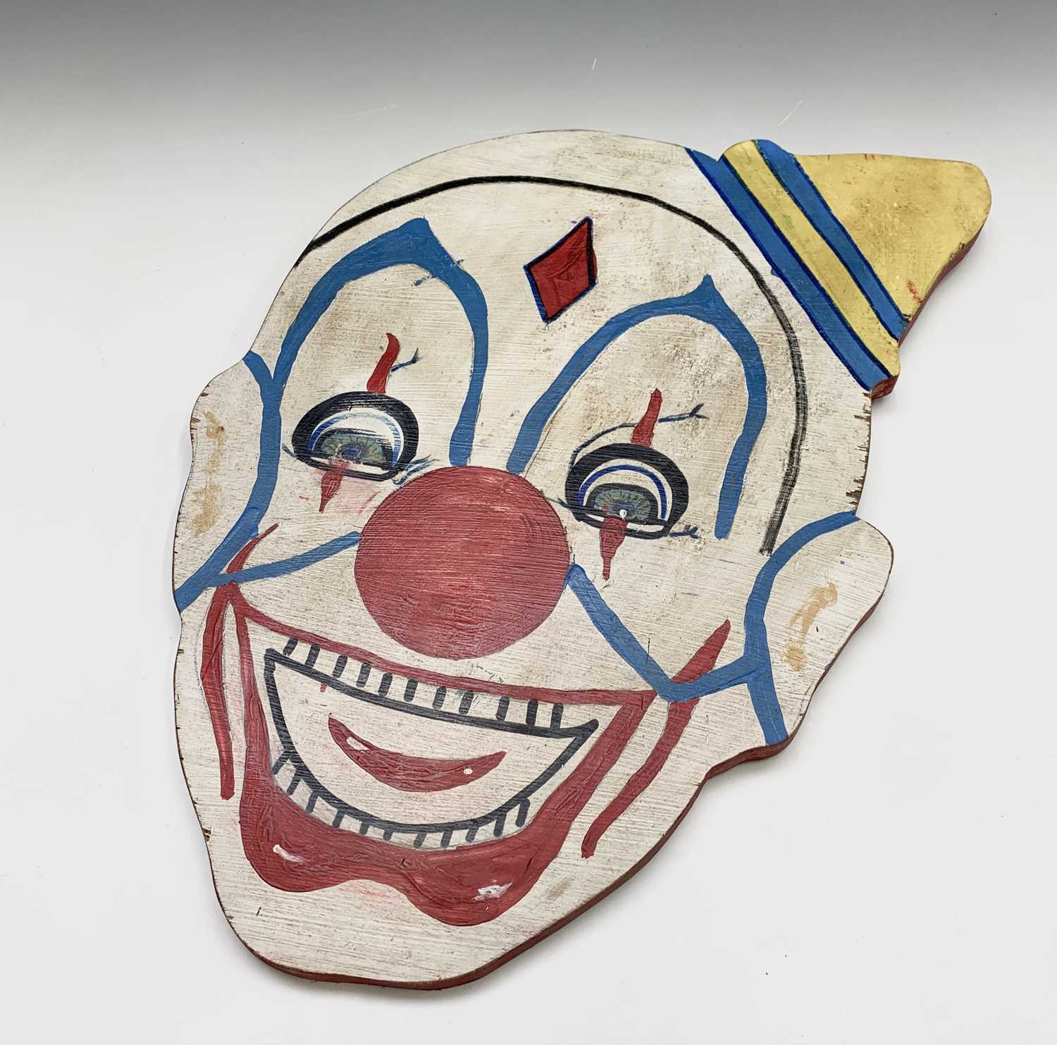 A clown head painted on wood. 52cm x 35cm (irregular).