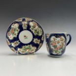 A Worcester scale blue ground cup and saucer, circa 1770, painted with polychrome floral panels
