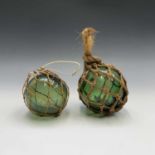Two green glass fishing floats. Largest 14cm diameter.