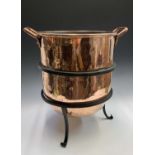 A Victorian twin handled copper cauldron or log bin, height 44cm, on a later wrought iron stand.