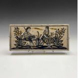 A 20th century Spanish faience tile, hand painted with a young couple sitting on a fence, painted